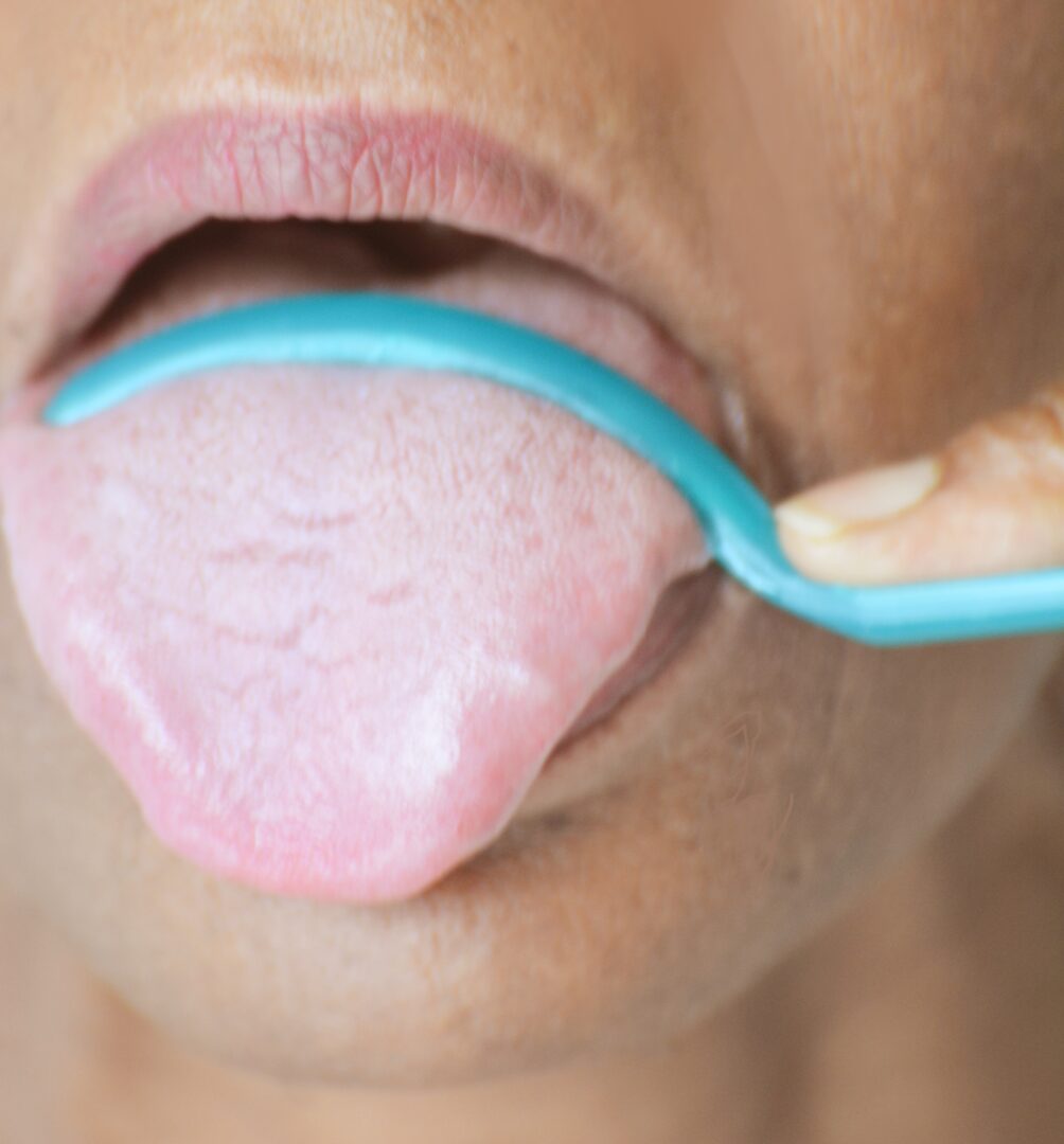 A person with their tongue hanging out brushing it.